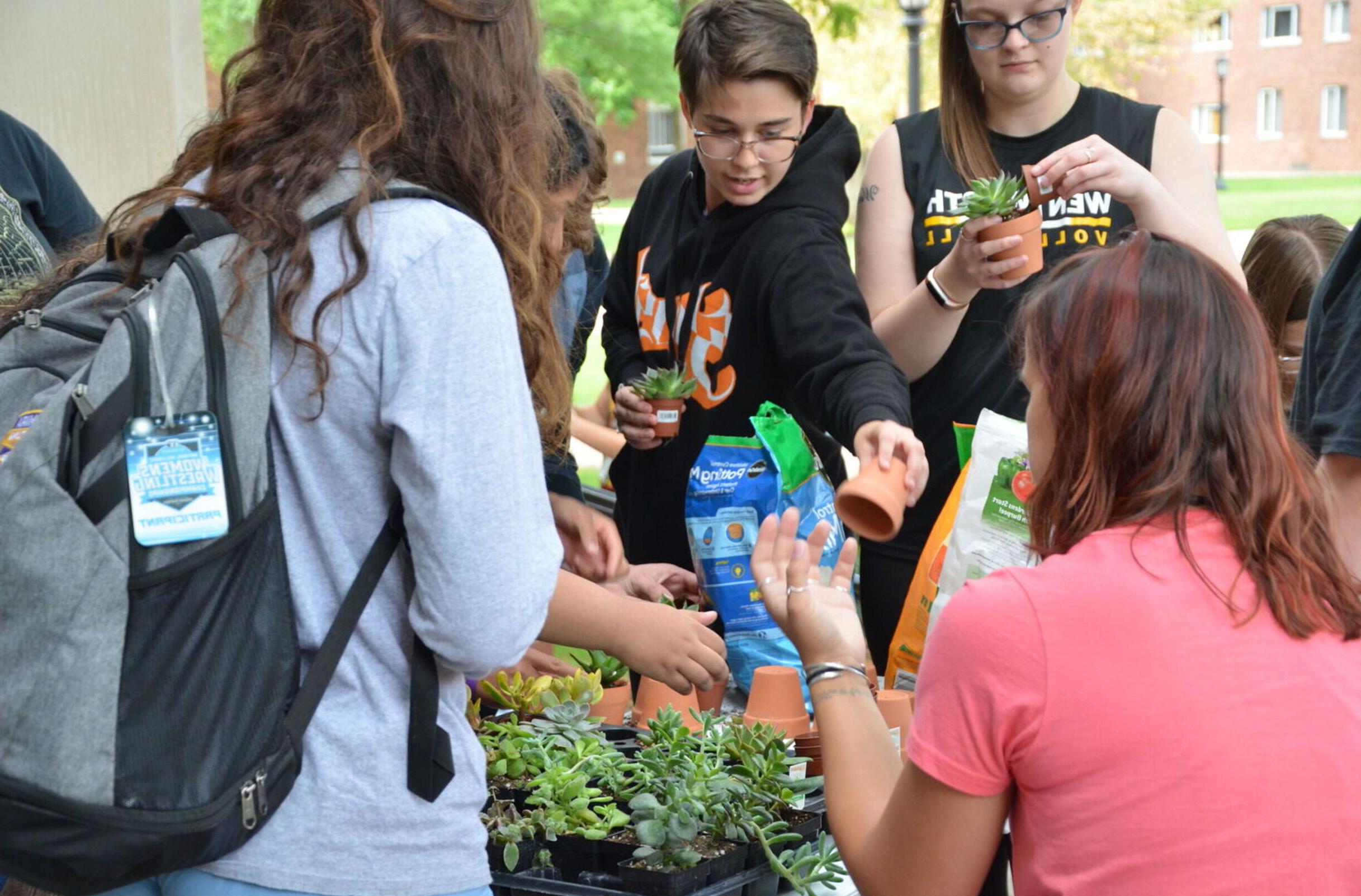 Students do a planting activity at the 环保俱乐部's table during the Club 和 组织 Fair